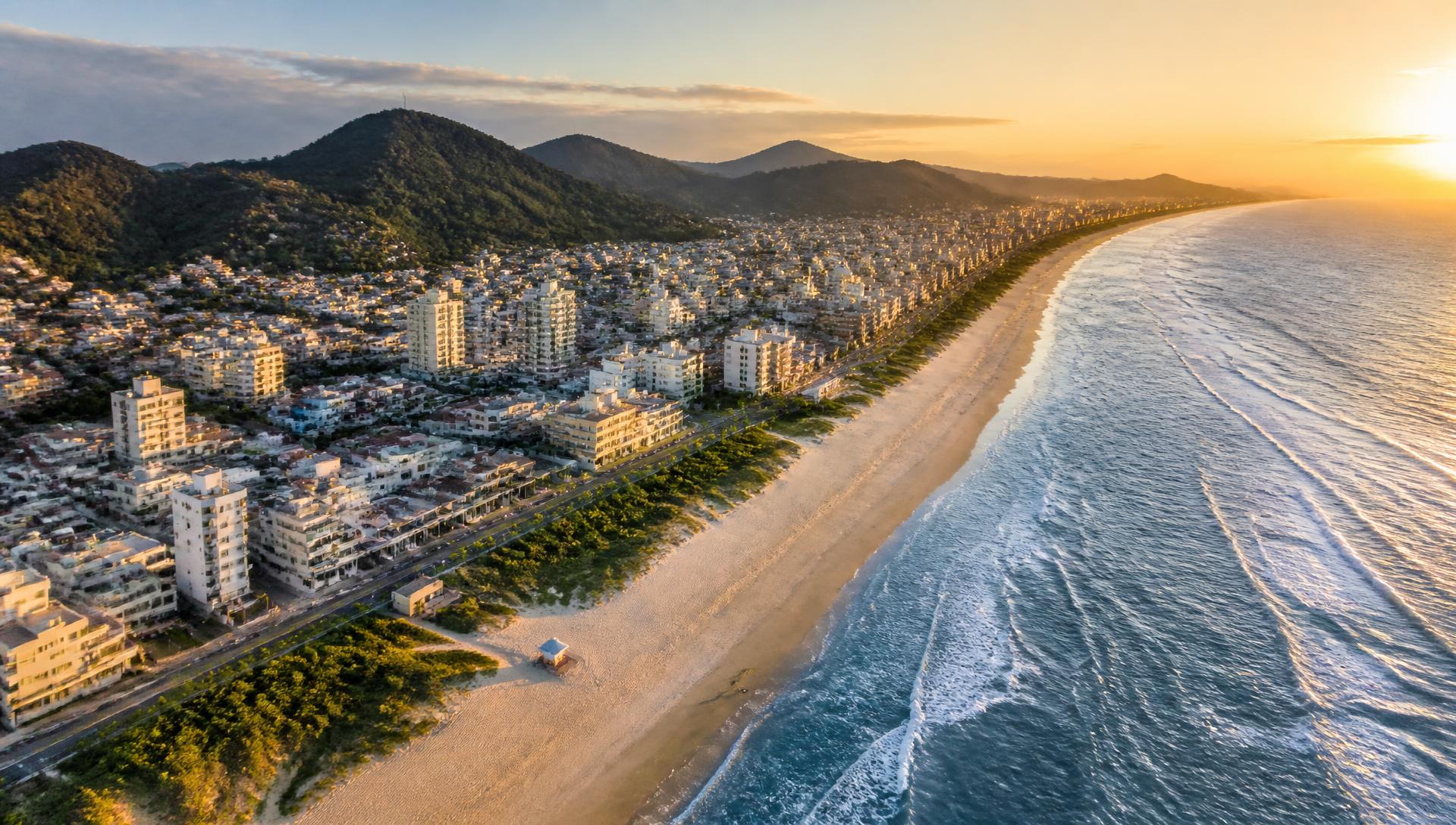 Vista aérea do litoral e da orla urbanizada de Matinhos, Paraná, ao pôr do sol